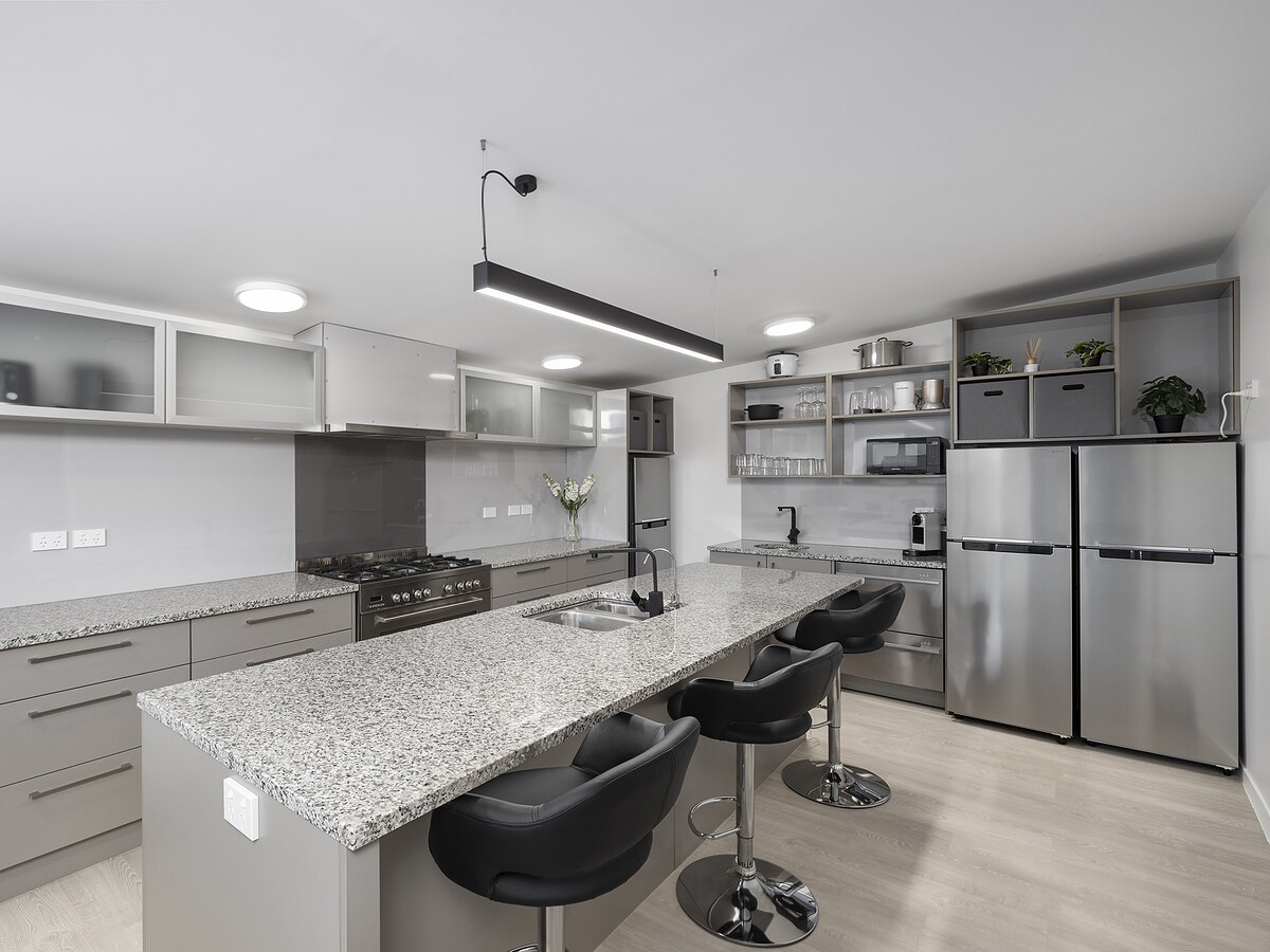 The George Wing chef's kitchen — granite island, gas range, three stools
