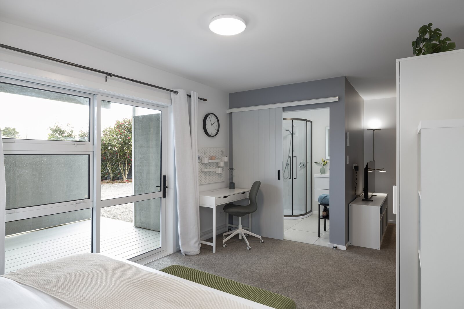 A suite from the bed — desk, ensuite and doors to the deck
